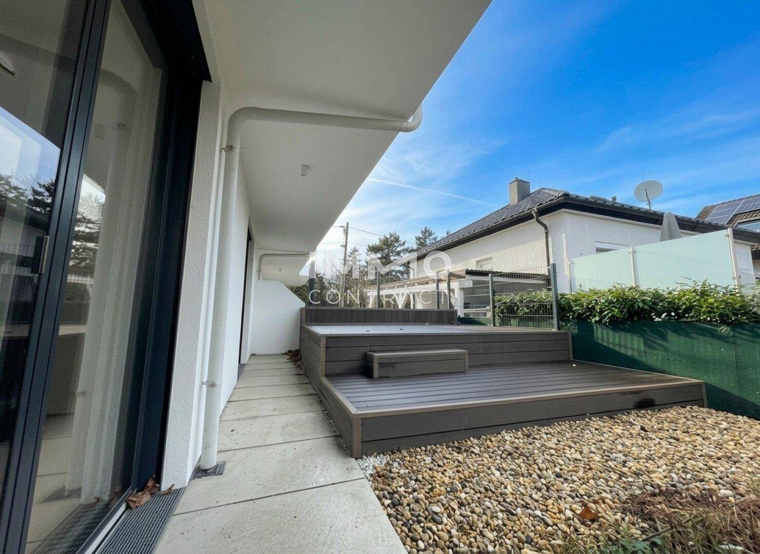 Erhöhter Holzterrassenbereich mit Kiesfläche, ideal für Entspannung im Freien.