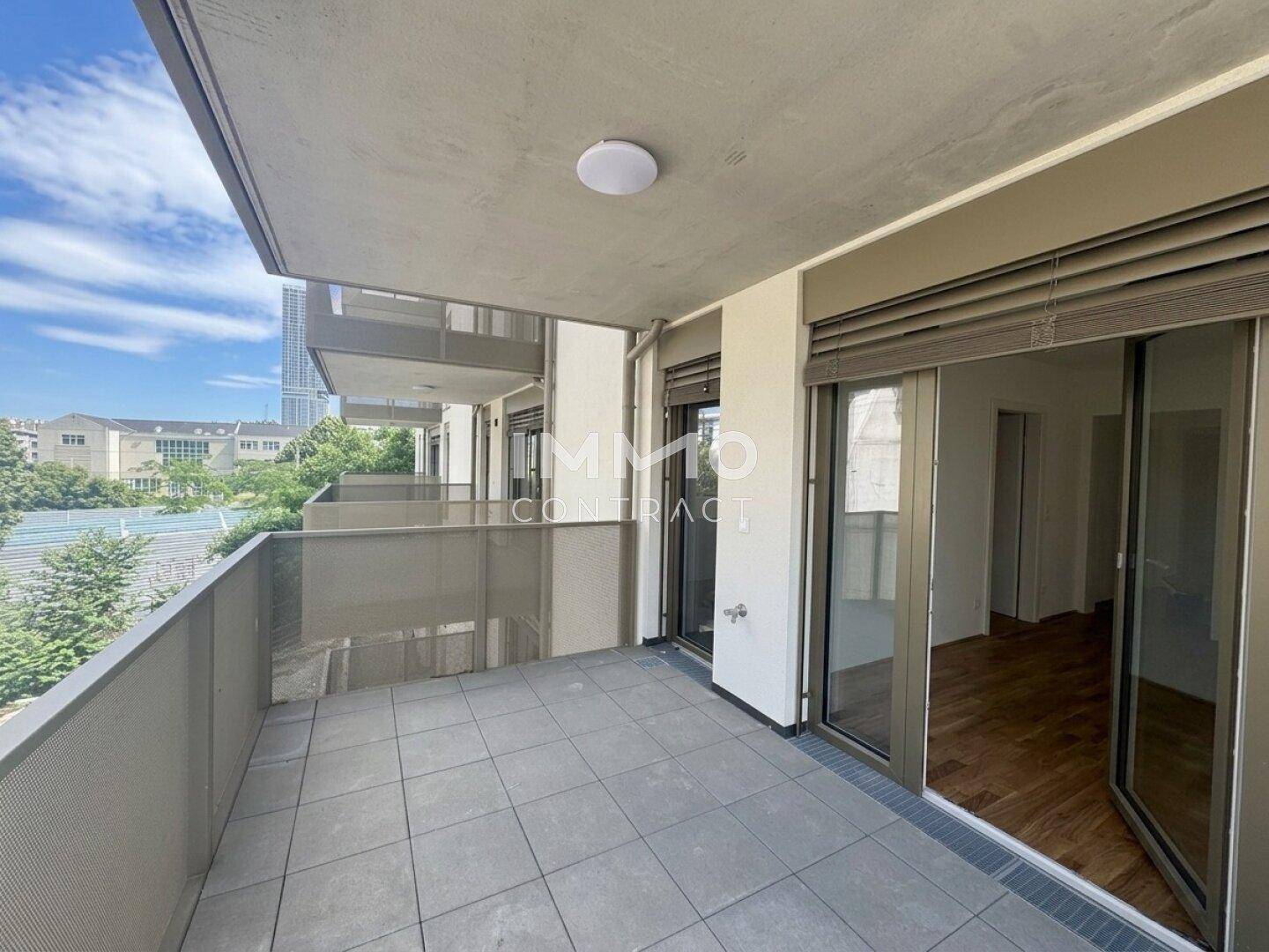 Geräumiger Balkon mit Fliesenboden und Blick auf die umliegenden Gebäude.