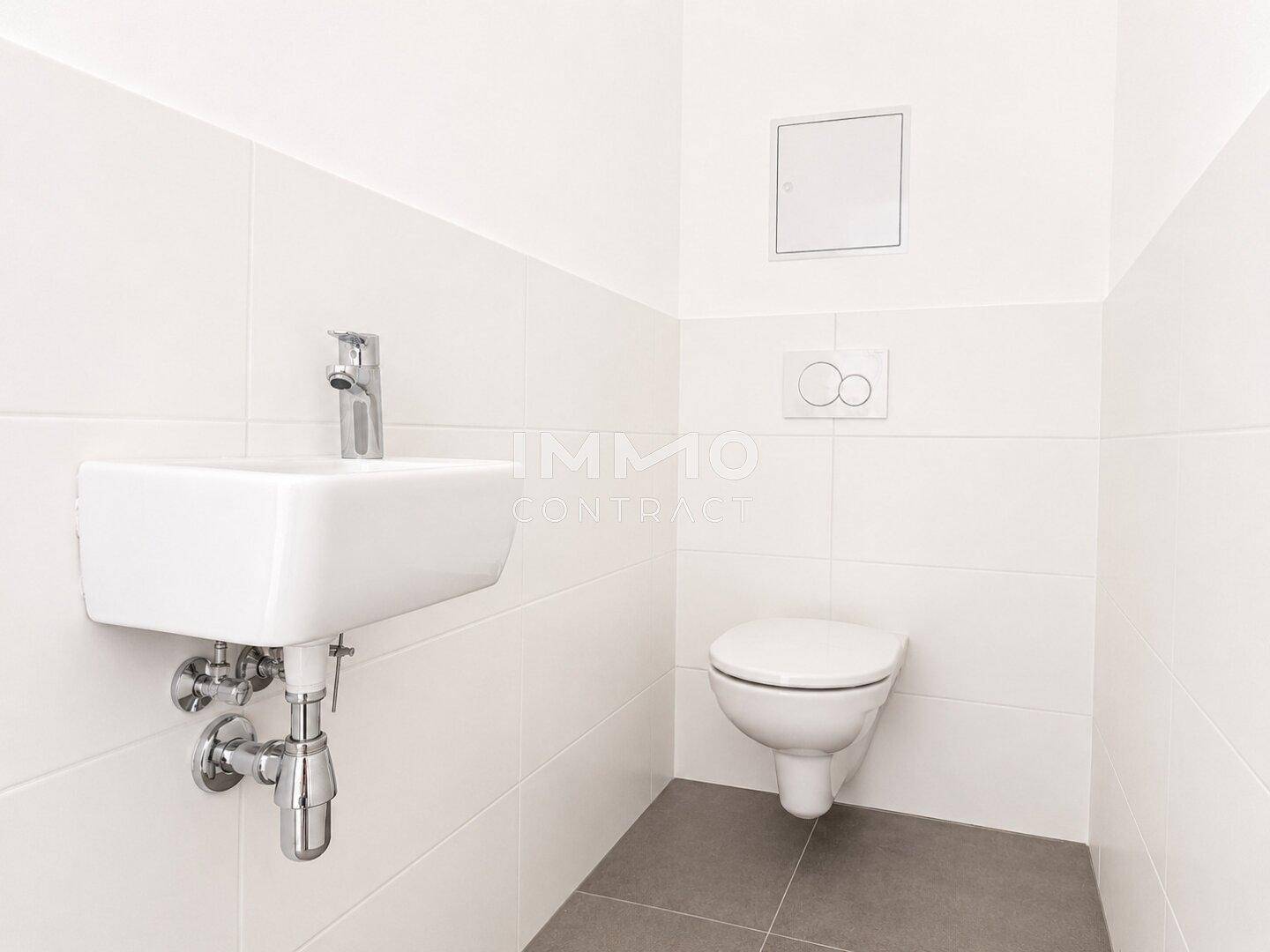 Kleines Gäste-WC mit wandhängender Toilette, modernem Waschbecken und grauen Bodenfliesen.