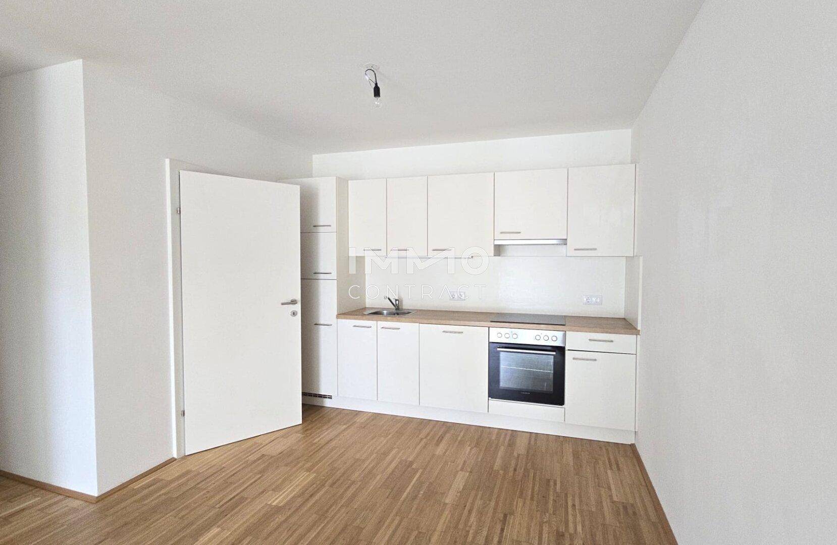 Funktionale Küchenzeile in Weiß mit Holzdetails und allen notwendigen Geräten, ideal für kleine Wohnungen.