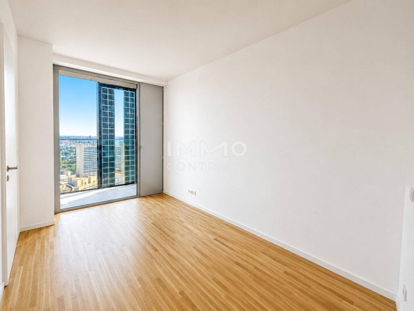 Geräumiges Schlafzimmer mit Parkettboden und großen Fenstern, die viel Tageslicht hereinlassen.