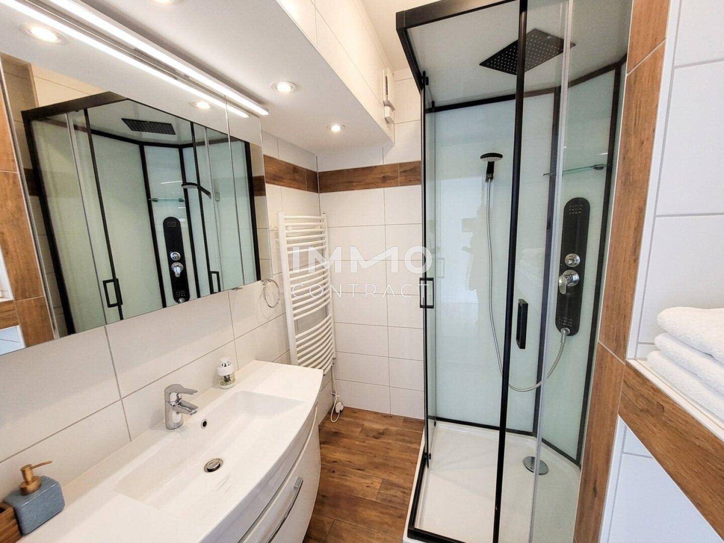 Modernes Badezimmer mit Duschkabine, Waschtisch und beheiztem Handtuchhalter.