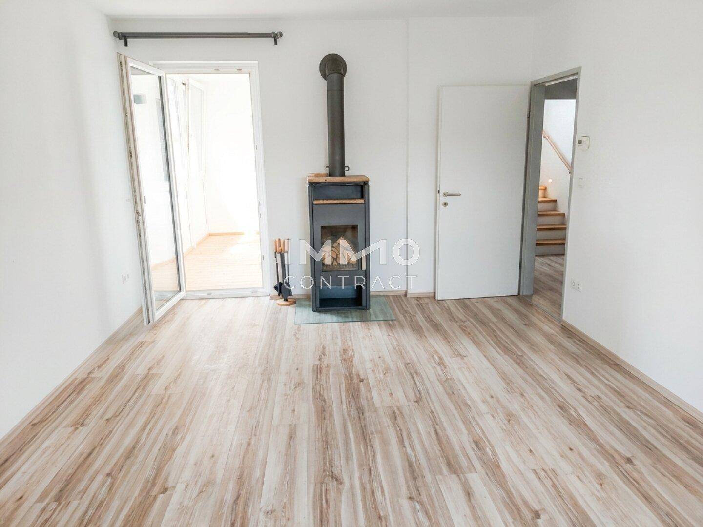 Geräumiges Wohnzimmer mit modernem Holzofen und hellem Laminatboden.