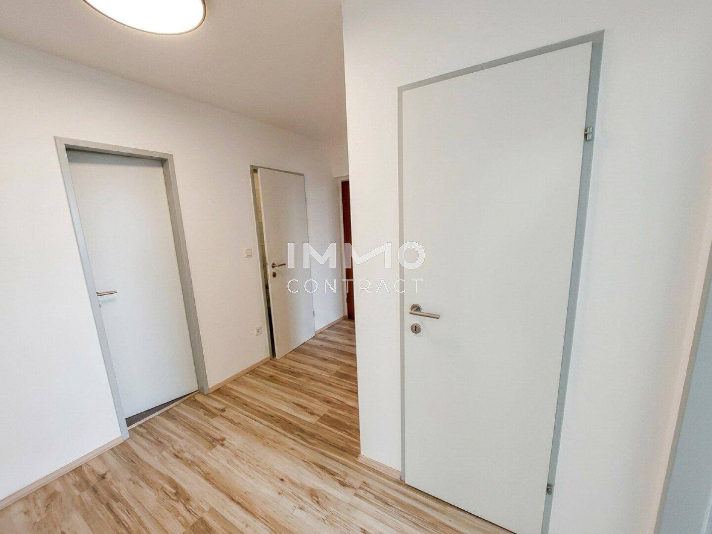Heller Flur mit Laminatboden und mehreren Türen zu den angrenzenden Zimmern.