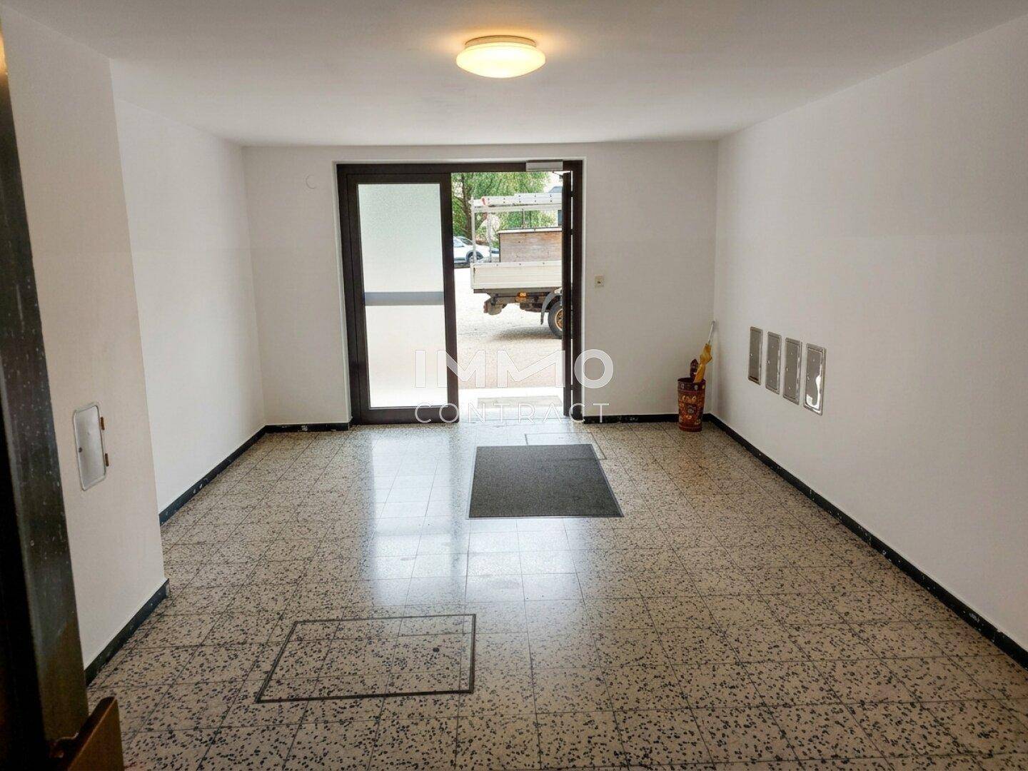 Eingangsbereich mit Fliesenboden und Zugang zum Gebäudeinneren und Außenbereich.