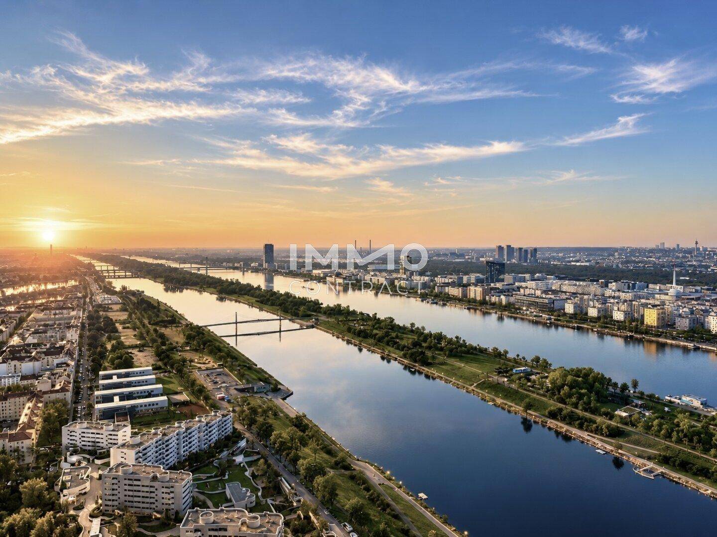 Weitläufige Luftaufnahme einer Stadt mit breitem Fluss, Brücken und Gebäuden bei Sonnenuntergang.
