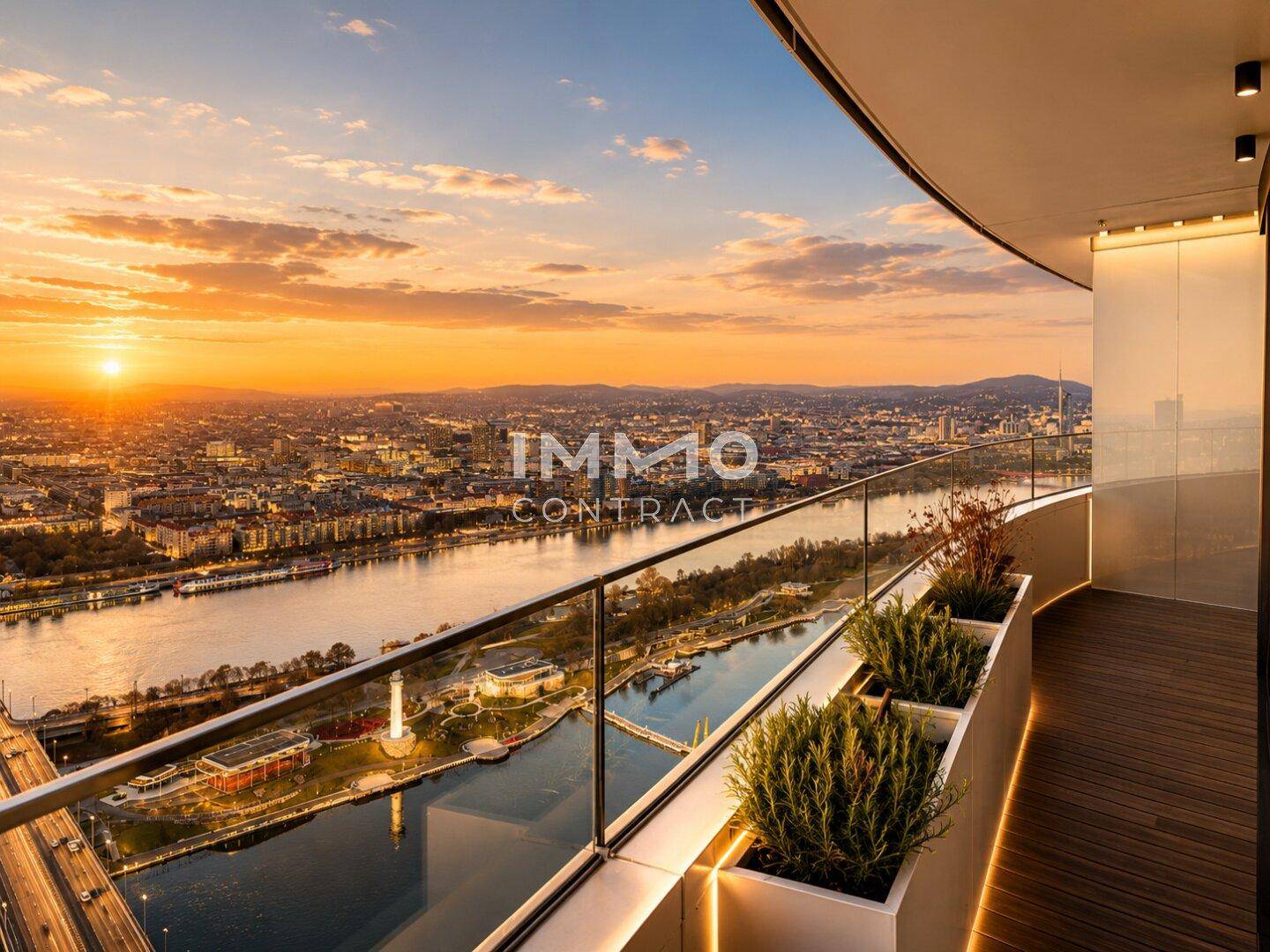 Geräumiger Balkon mit Glasgeländer und Pflanzen, bietet einen weiten Blick auf die Stadt und den Fluss bei Sonnenuntergang.