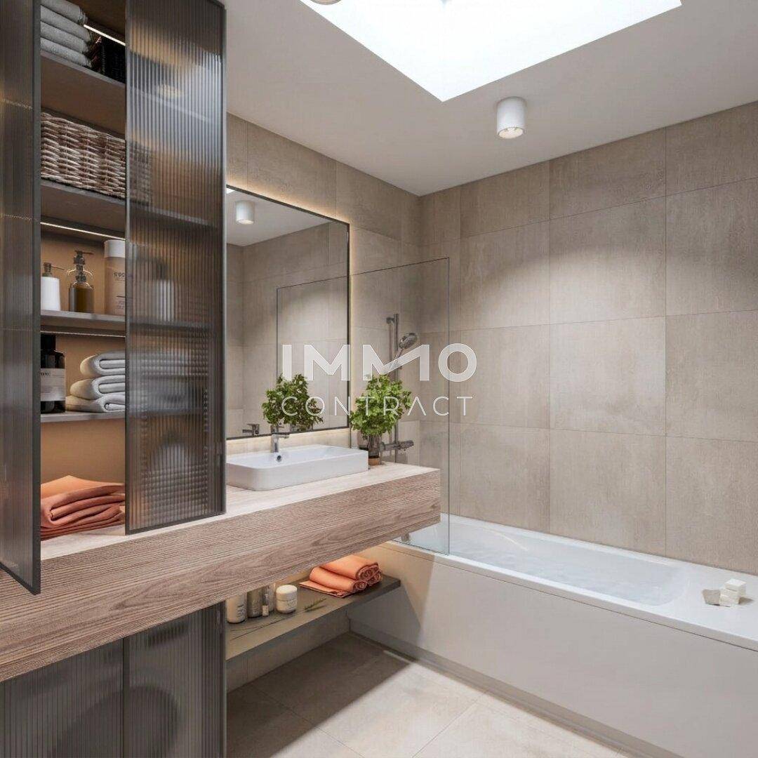 Modernes Badezimmer mit Badewanne, Einzelwaschbecken, großem Spiegel und natürlichem Licht durch ein Oberlicht.