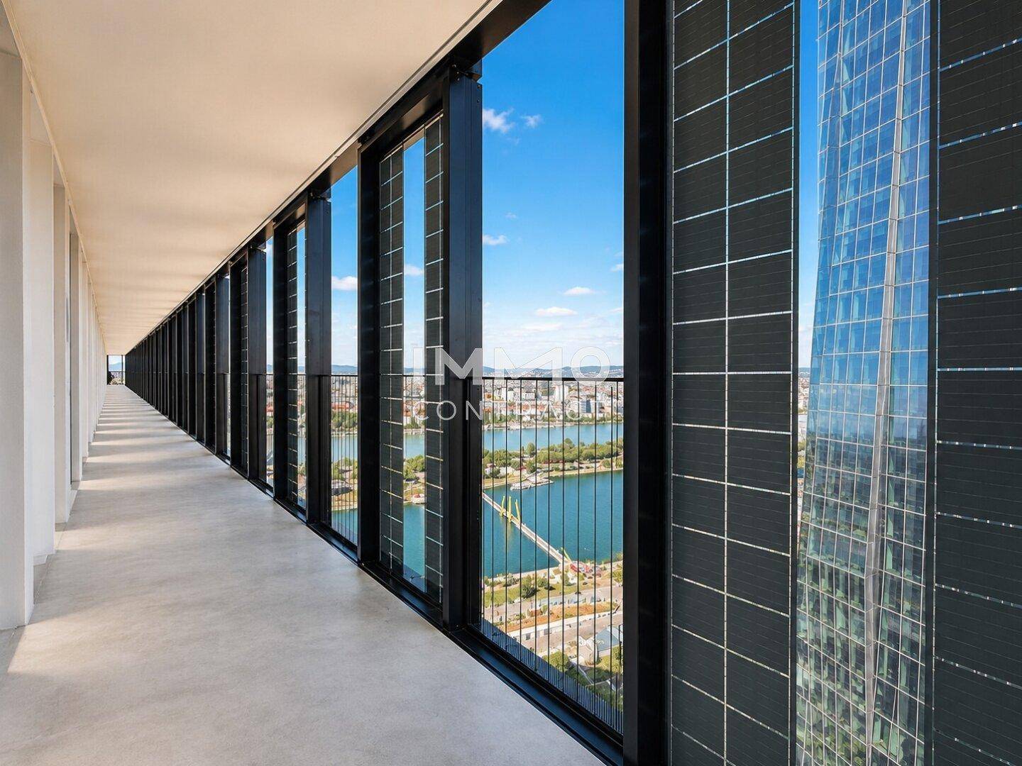 Langer Balkon mit beeindruckendem Blick auf die Stadt und das Wasser, umgeben von moderner Architektur.
