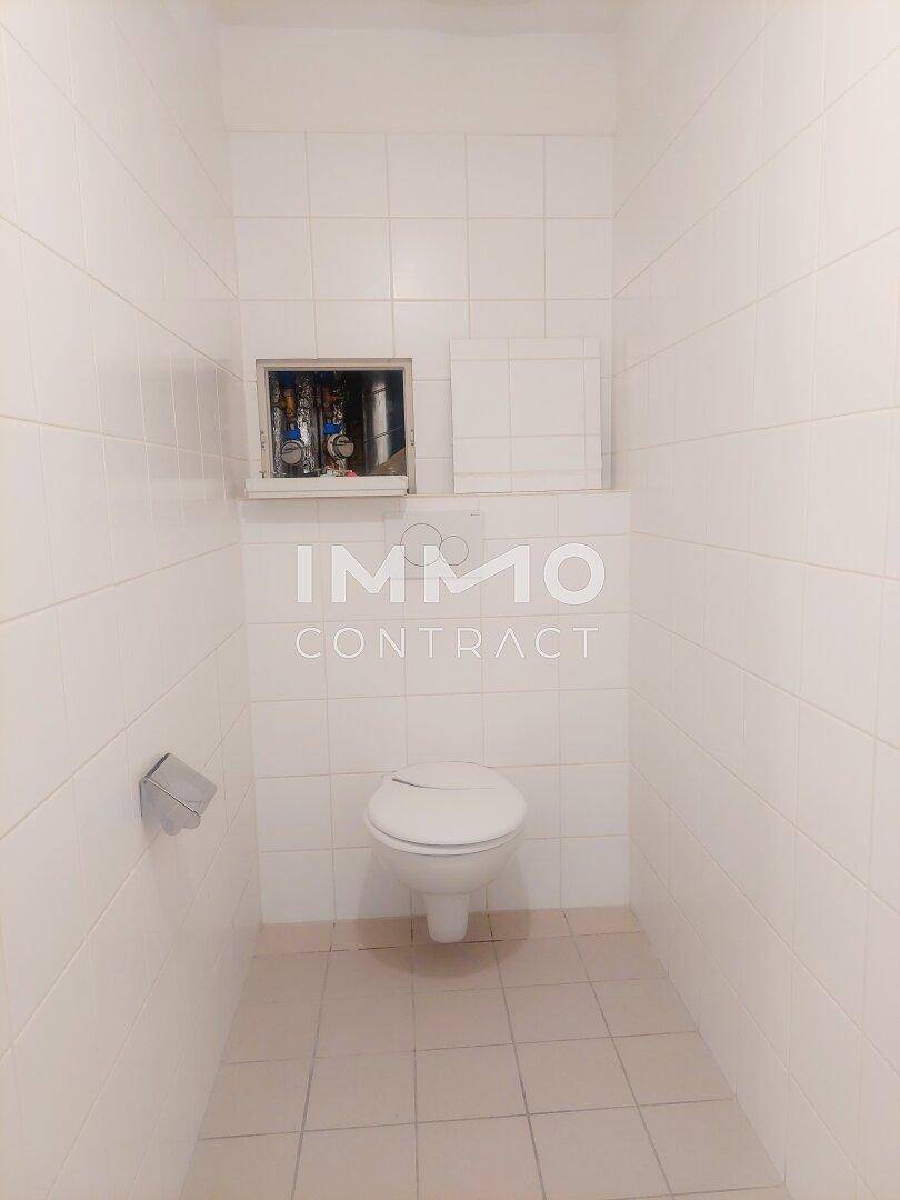 Separates WC mit weißen Fliesen an Wänden und Boden sowie einer Wandtoilette.
