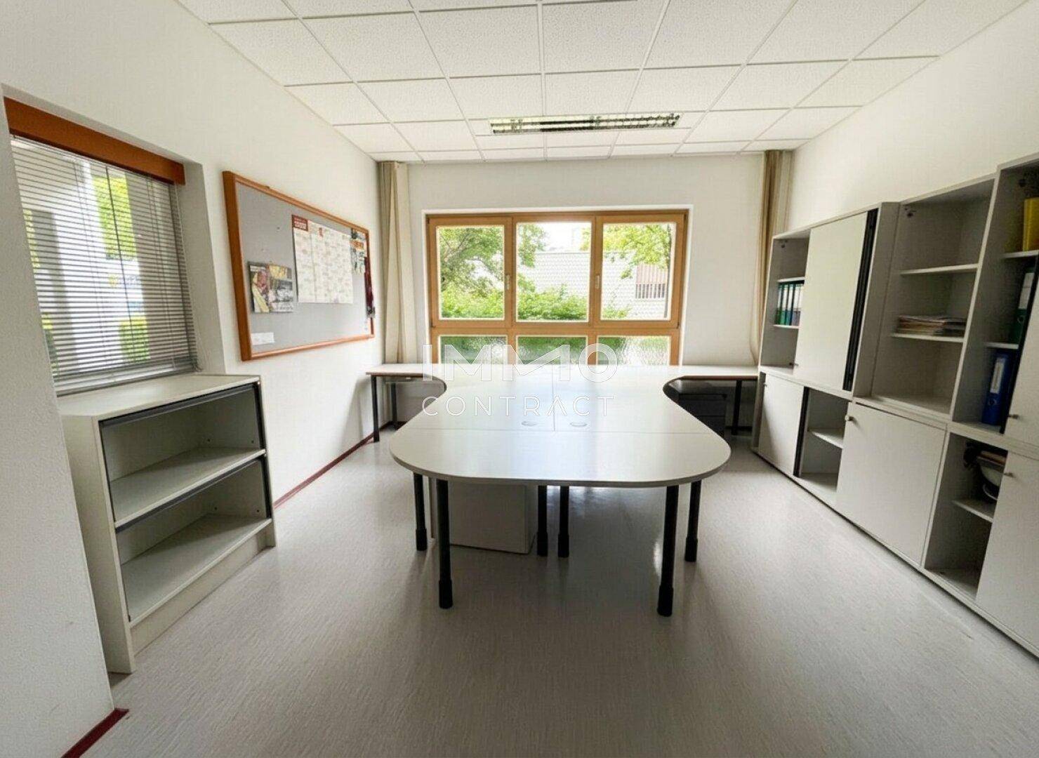 Helles Büro mit großen Fenstern, weißen Schreibtischen und Regalen, ideal für produktives Arbeiten.