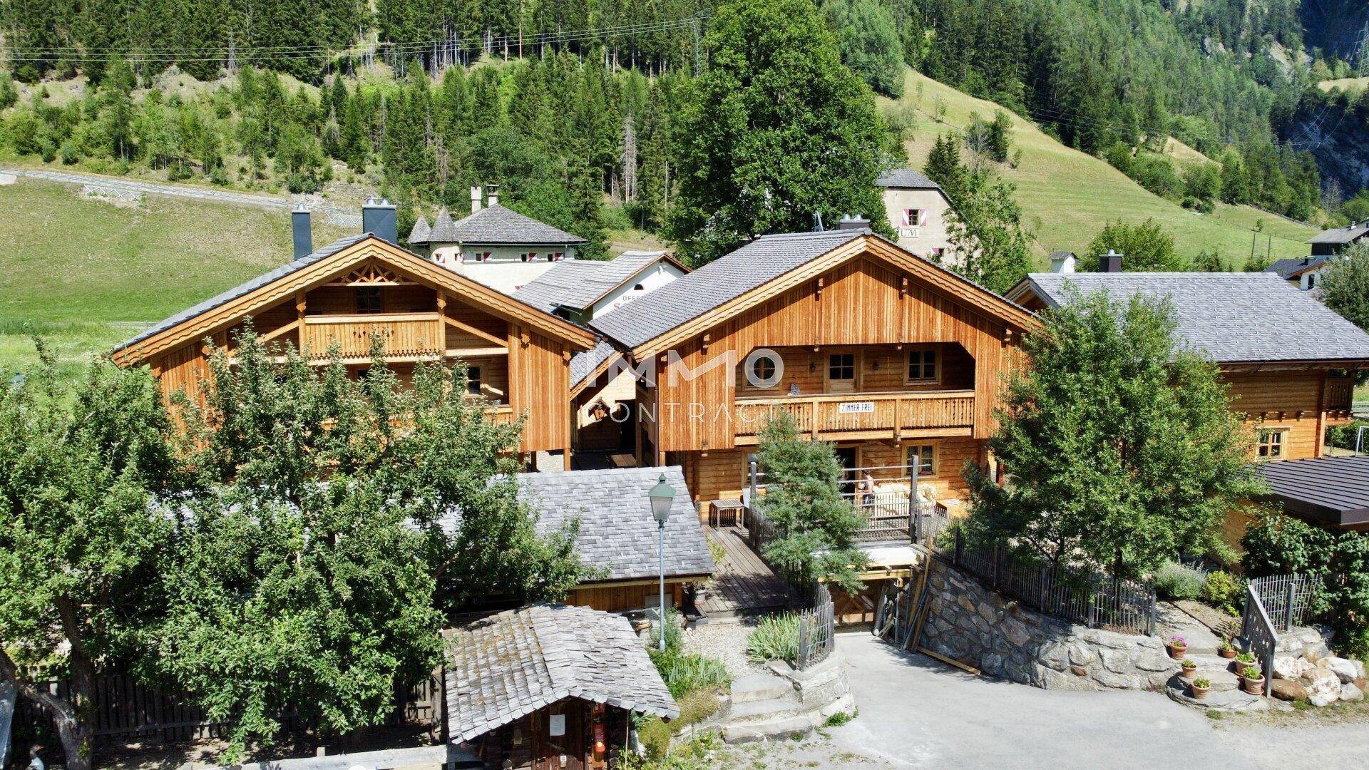 Mehrere Holzchalets in traditionellem Stil, eingebettet in eine grüne Berglandschaft.