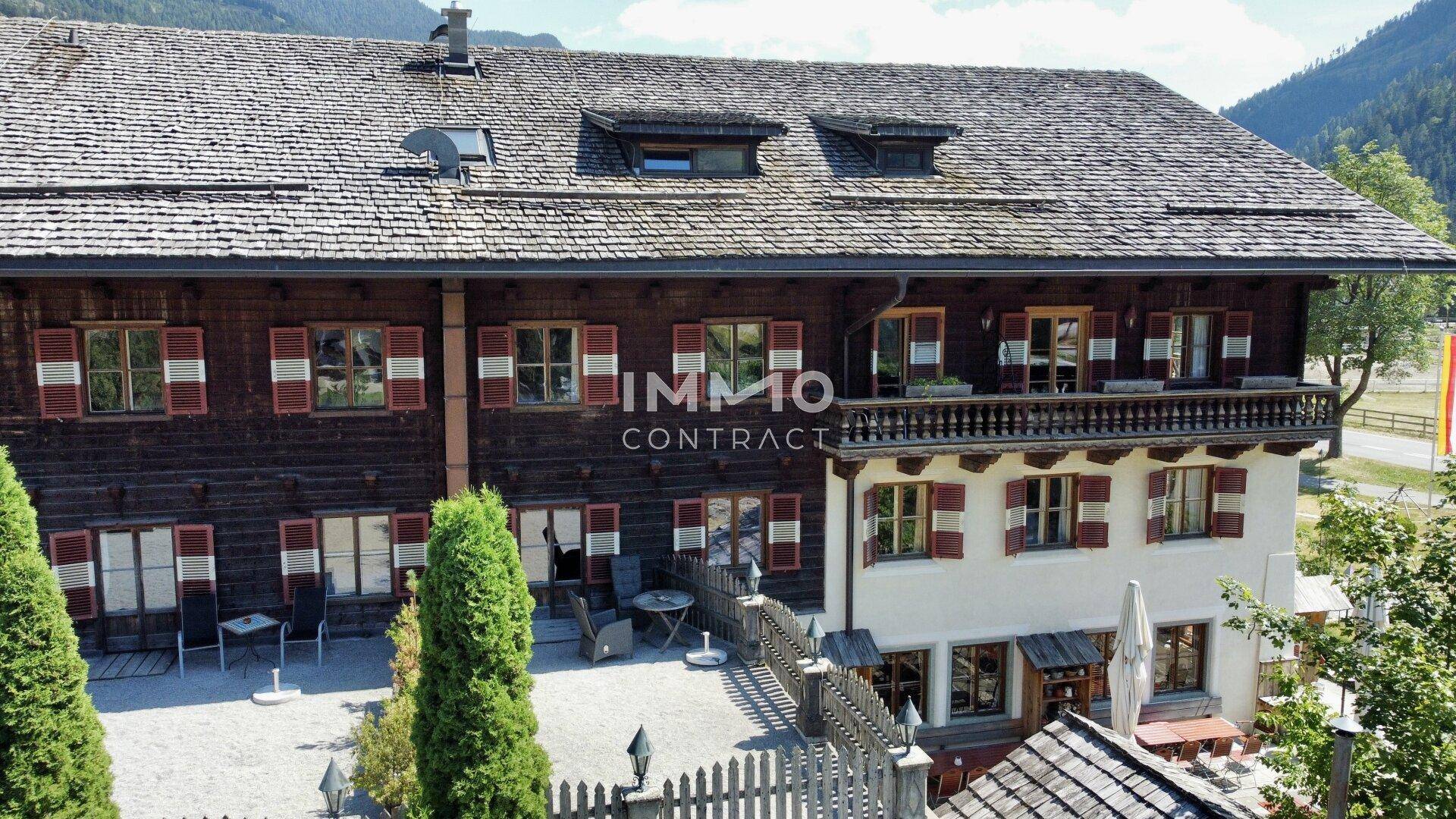 Nahaufnahme der Holzfassade eines traditionellen Gebäudes mit roten Fensterläden und Außenterrasse.