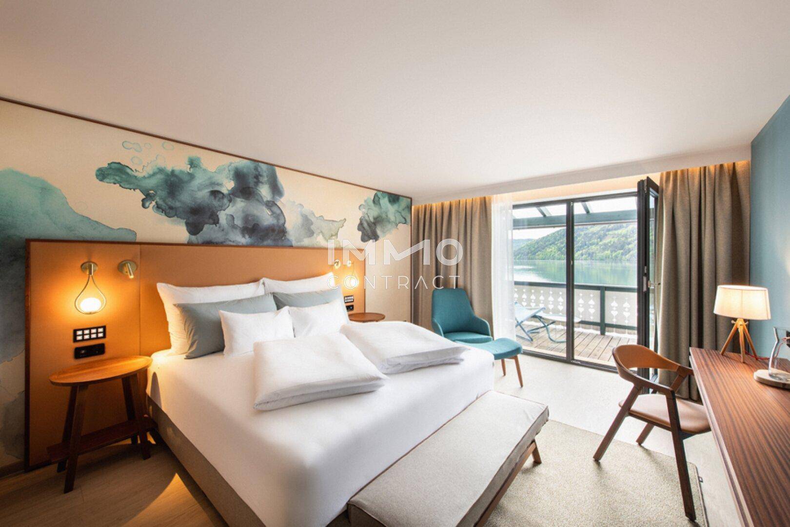 Stilvolles Schlafzimmer mit Seeblick, Balkonzugang und moderner Wandgestaltung in Blautönen.
