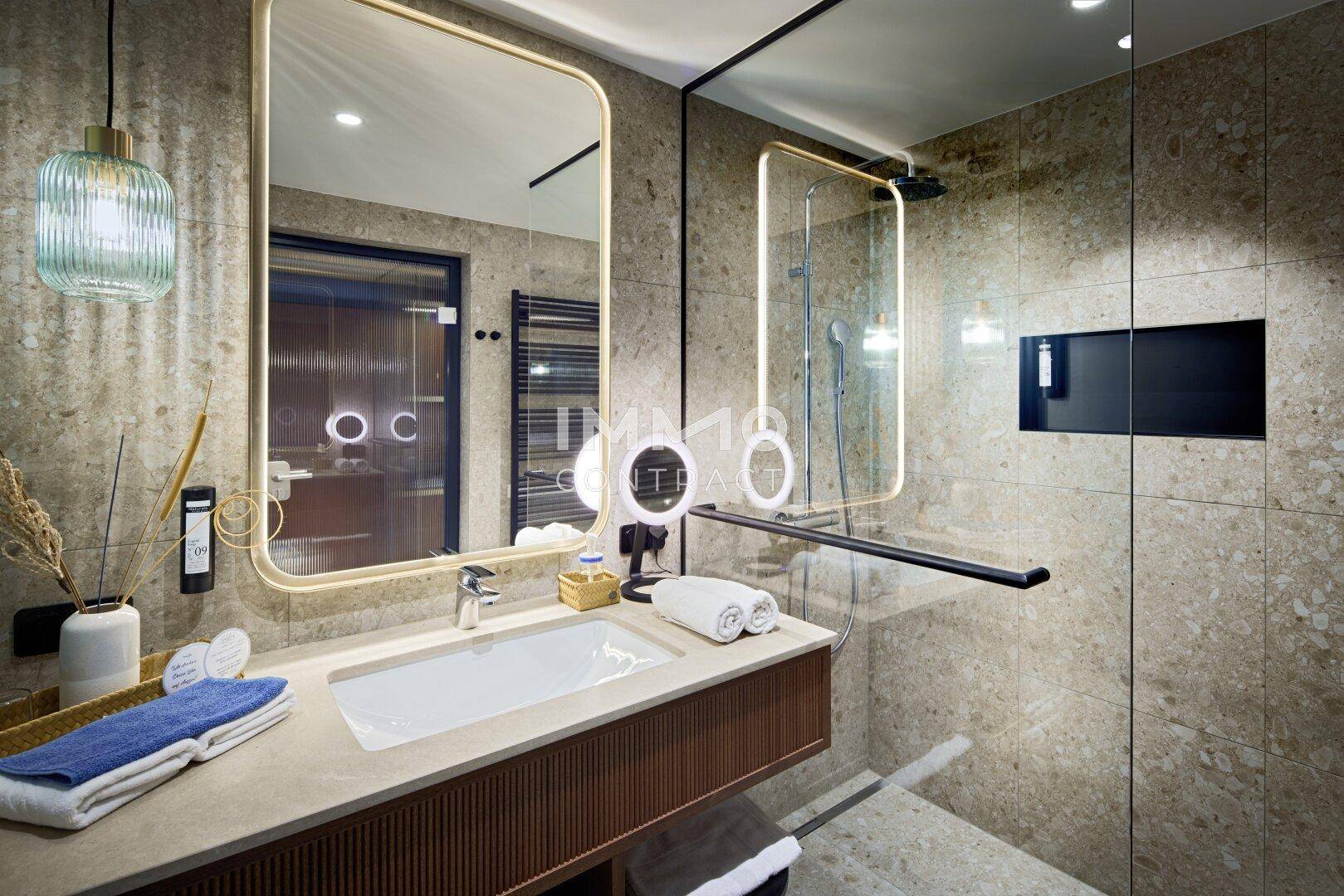 Modernes Badezimmer mit großem Spiegel, Einzelwaschbecken und begehbarer Dusche in hellen Naturtönen.