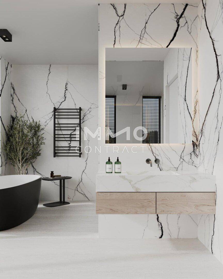 Luxuriöses Badezimmer mit Marmorwänden, freistehender Badewanne und modernem Waschtisch.
