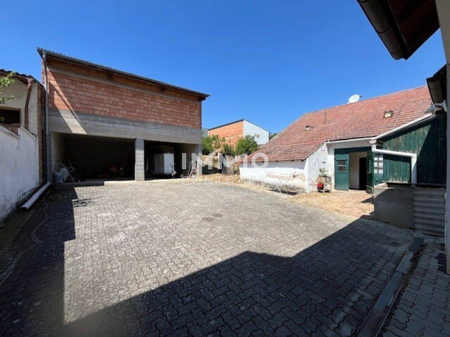 Gepflasterter Innenhof mit älterem Gebäude und einem Neubau im Hintergrund.