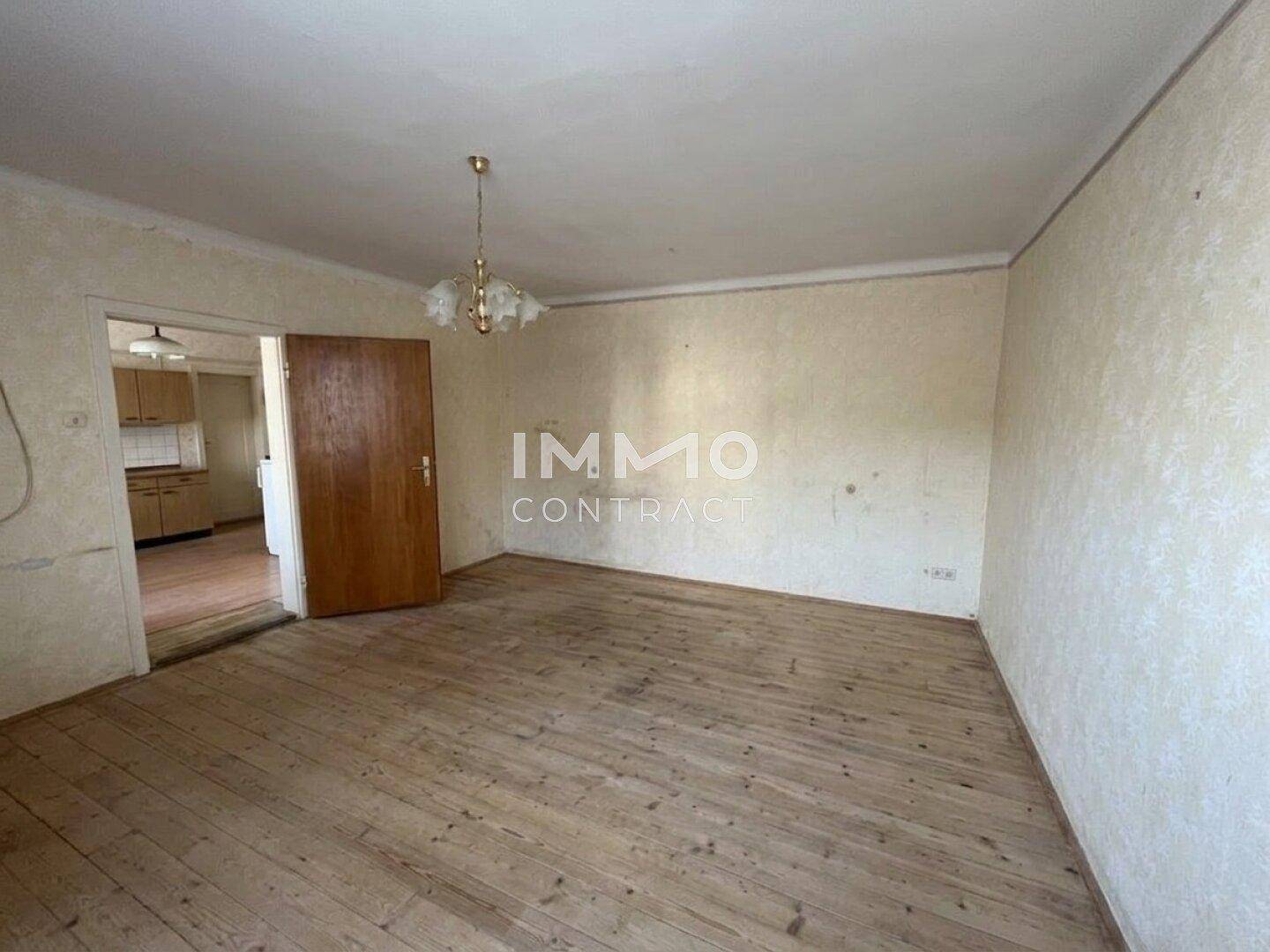Leeres Zimmer mit Holzdielenboden und Tapeten, bereit zur Renovierung und Gestaltung.