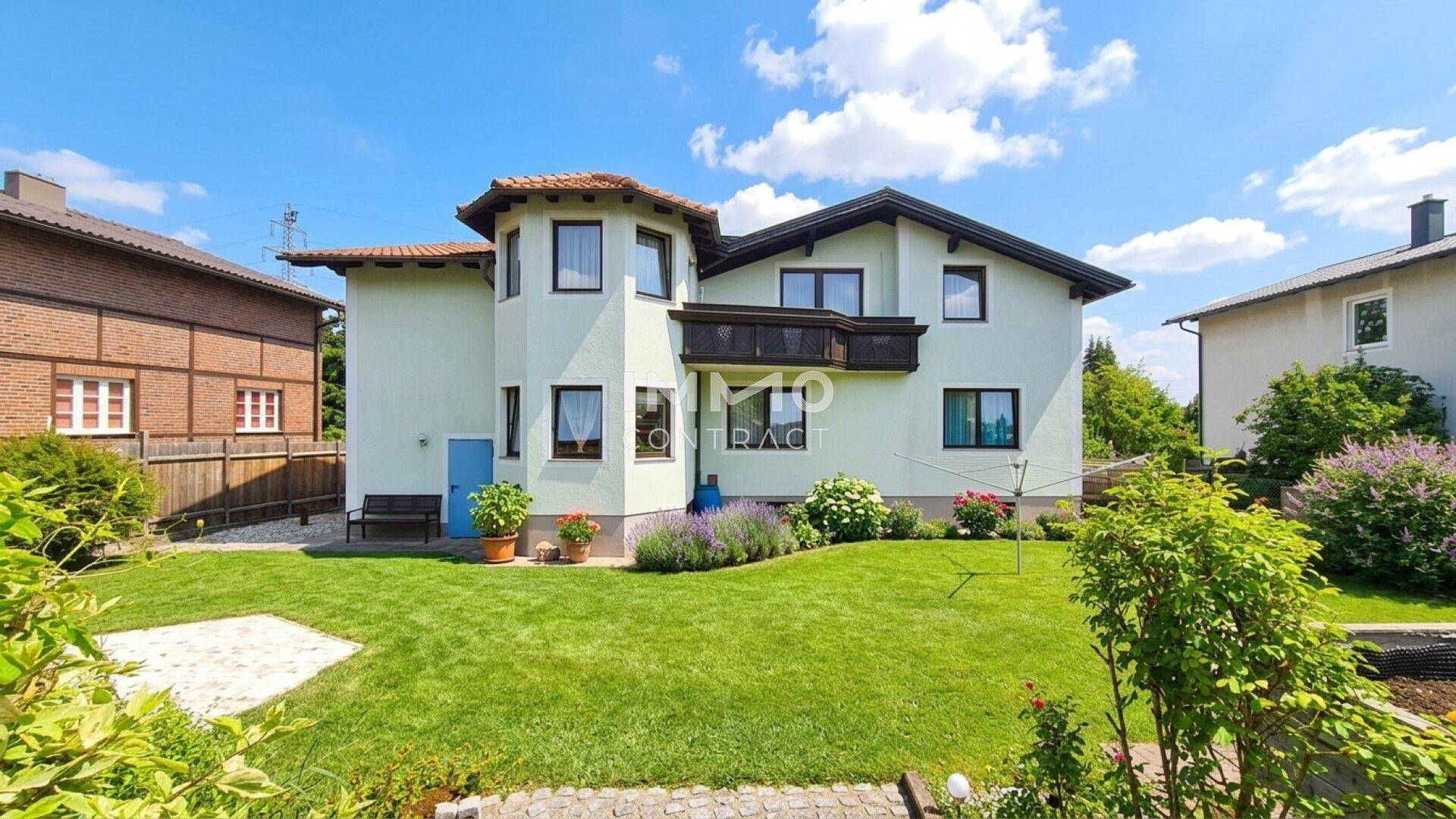 Rückseite des Hauses mit großem Rasen und gepflegtem Gartenbereich unter blauem Himmel.