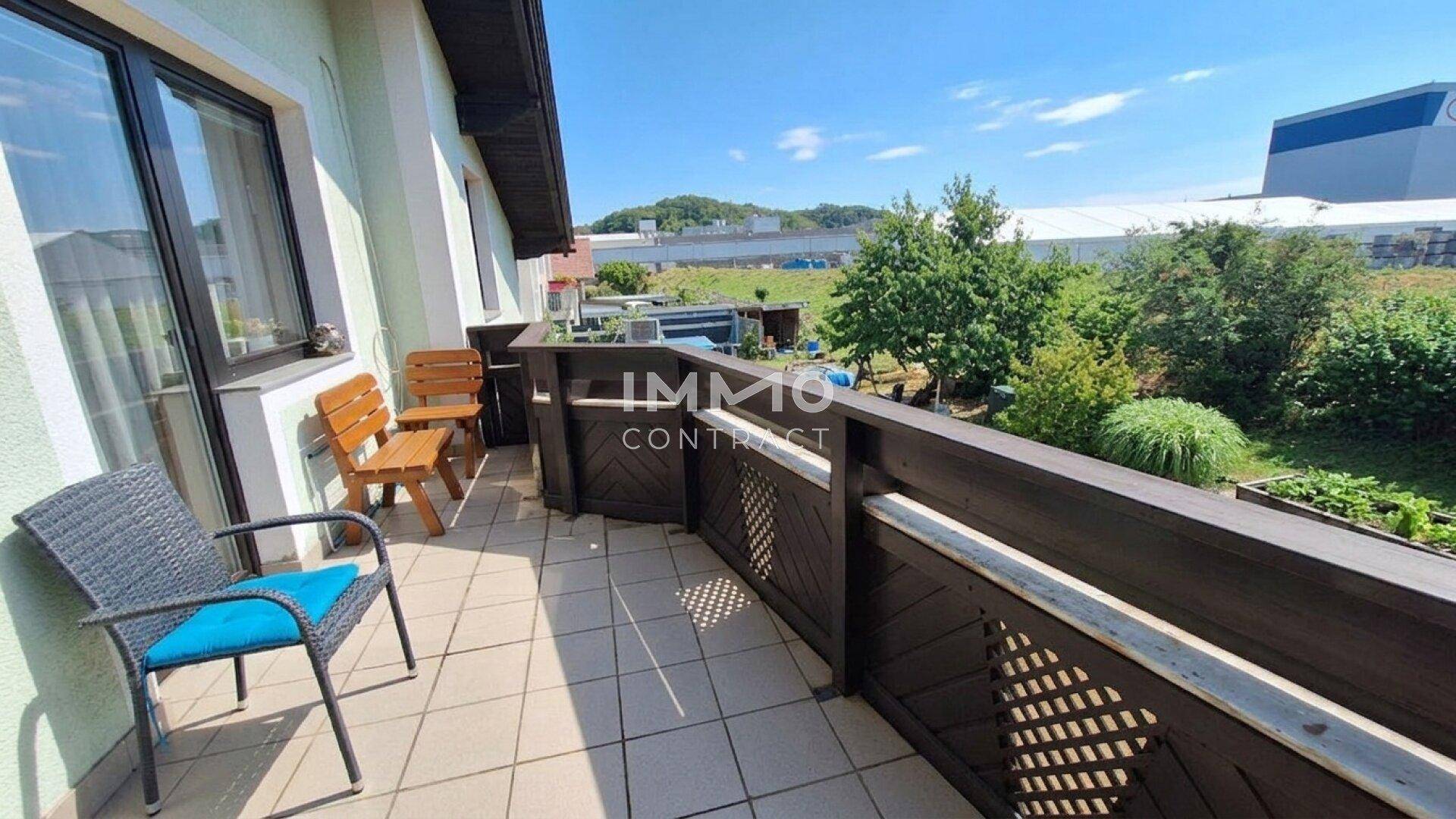 Balkon mit Fliesenboden und Sitzgelegenheiten, umgeben von grüner Landschaft und Weitblick.