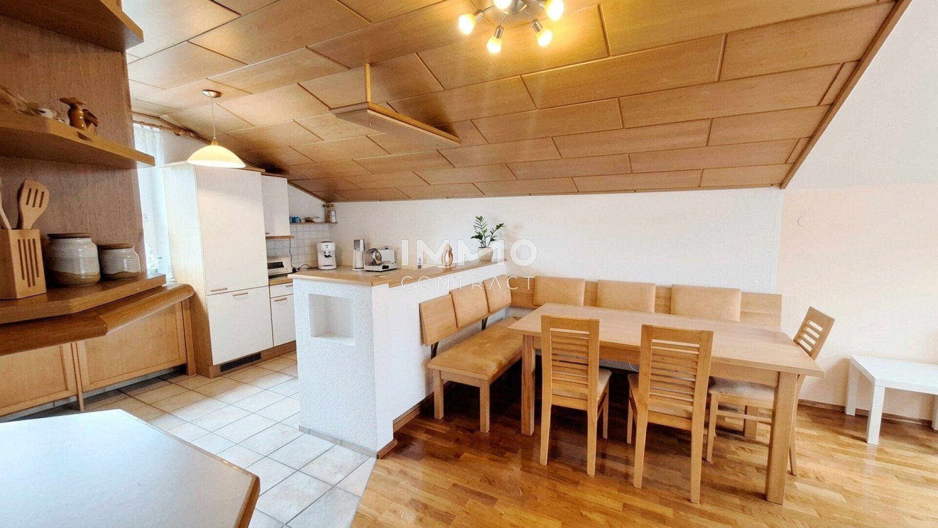Gemütliche Wohnküche mit Holzelementen, Essbereich und einer Kombination aus Fliesen- und Holzboden.