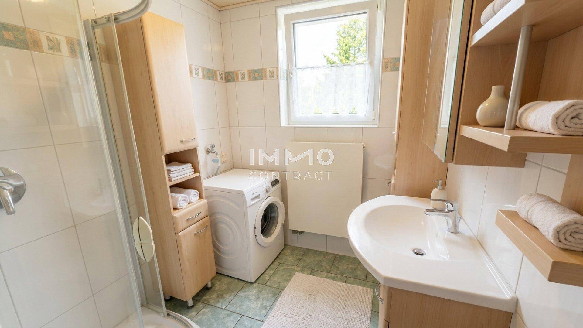 Badezimmer mit Dusche, Waschbecken, Waschmaschine und Fenster für natürliche Belüftung.