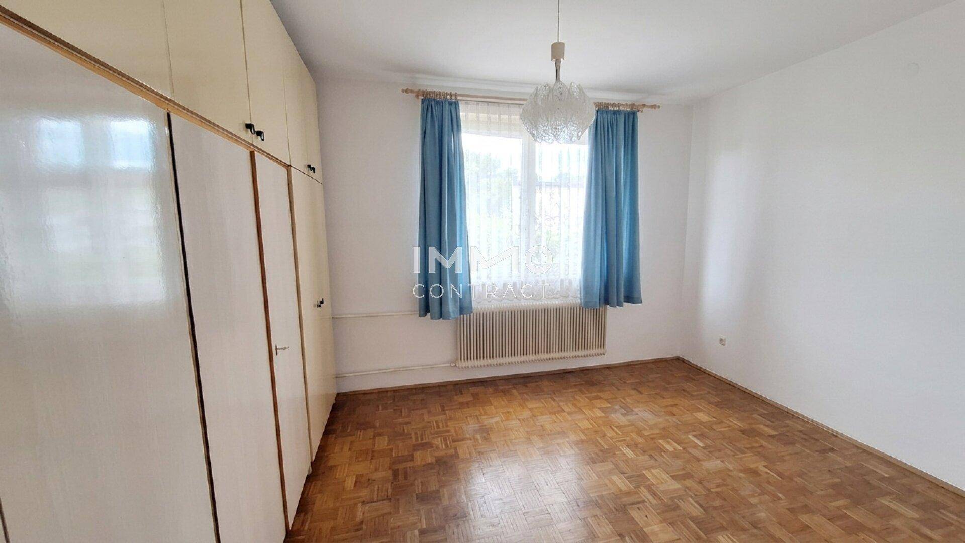 Schlafzimmer mit Holzboden, Einbauschränken und großem Fenster für viel Tageslicht.
