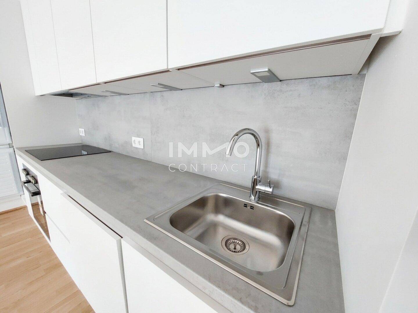 Moderne Küche mit weißen Schränken, Spülbecken und Induktionskochfeld.