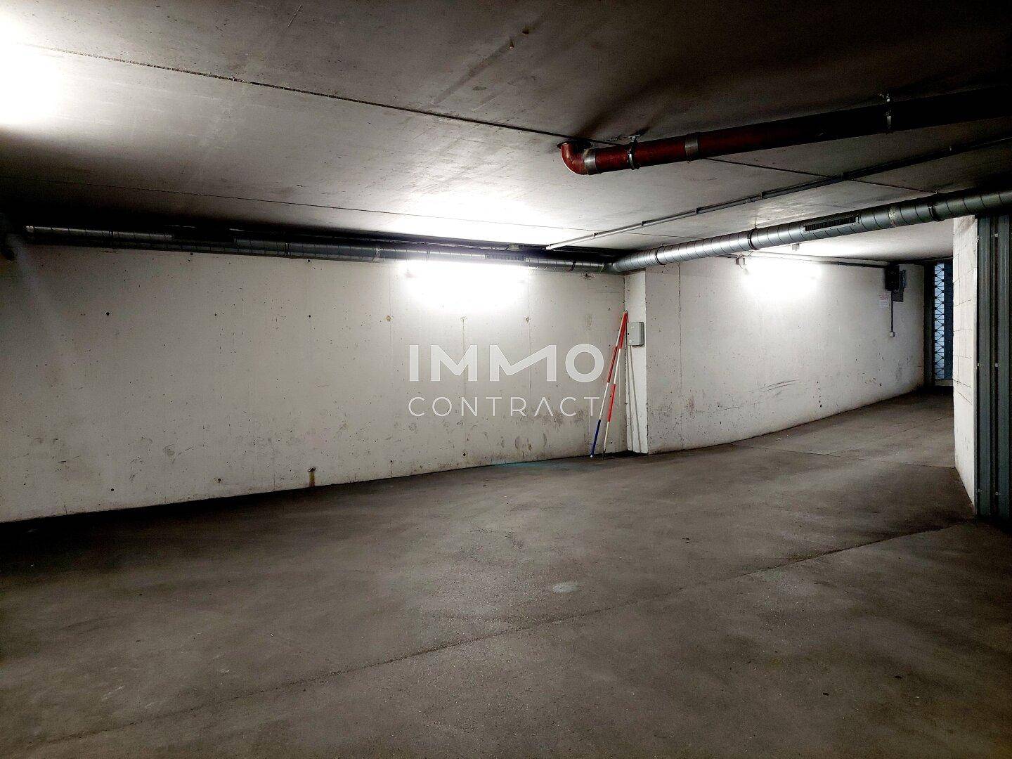 Geräumiger Bereich in einer Tiefgarage mit Betonwänden und Beleuchtung.