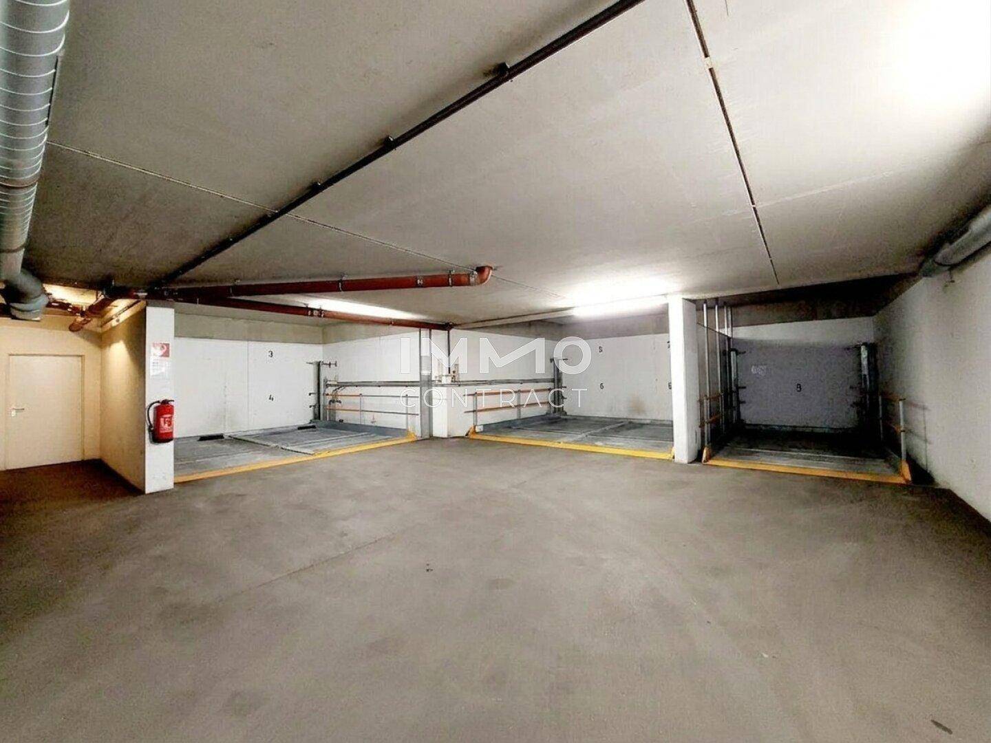 Mehrere mechanische Stapelparksysteme in einer sauberen und gut beleuchteten Tiefgarage.