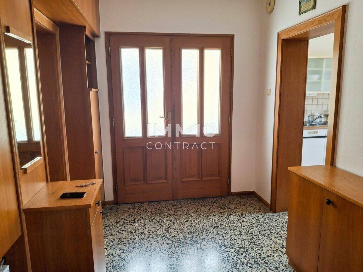 Eingangsbereich mit Holztüren, gemustertem Boden und Garderobenschrank.