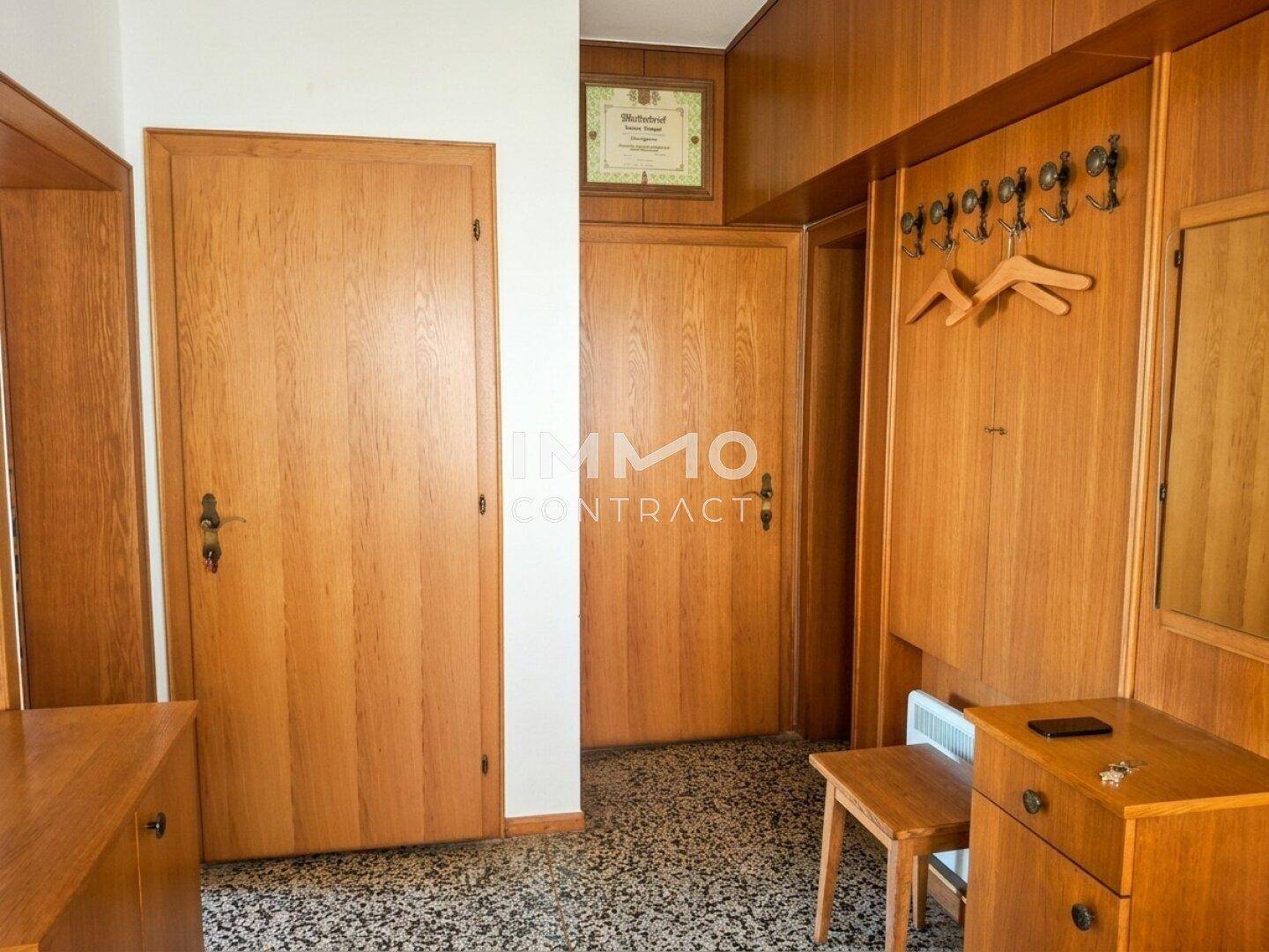 Flur mit Holzvertäfelung, Garderobe und zwei Holztüren.