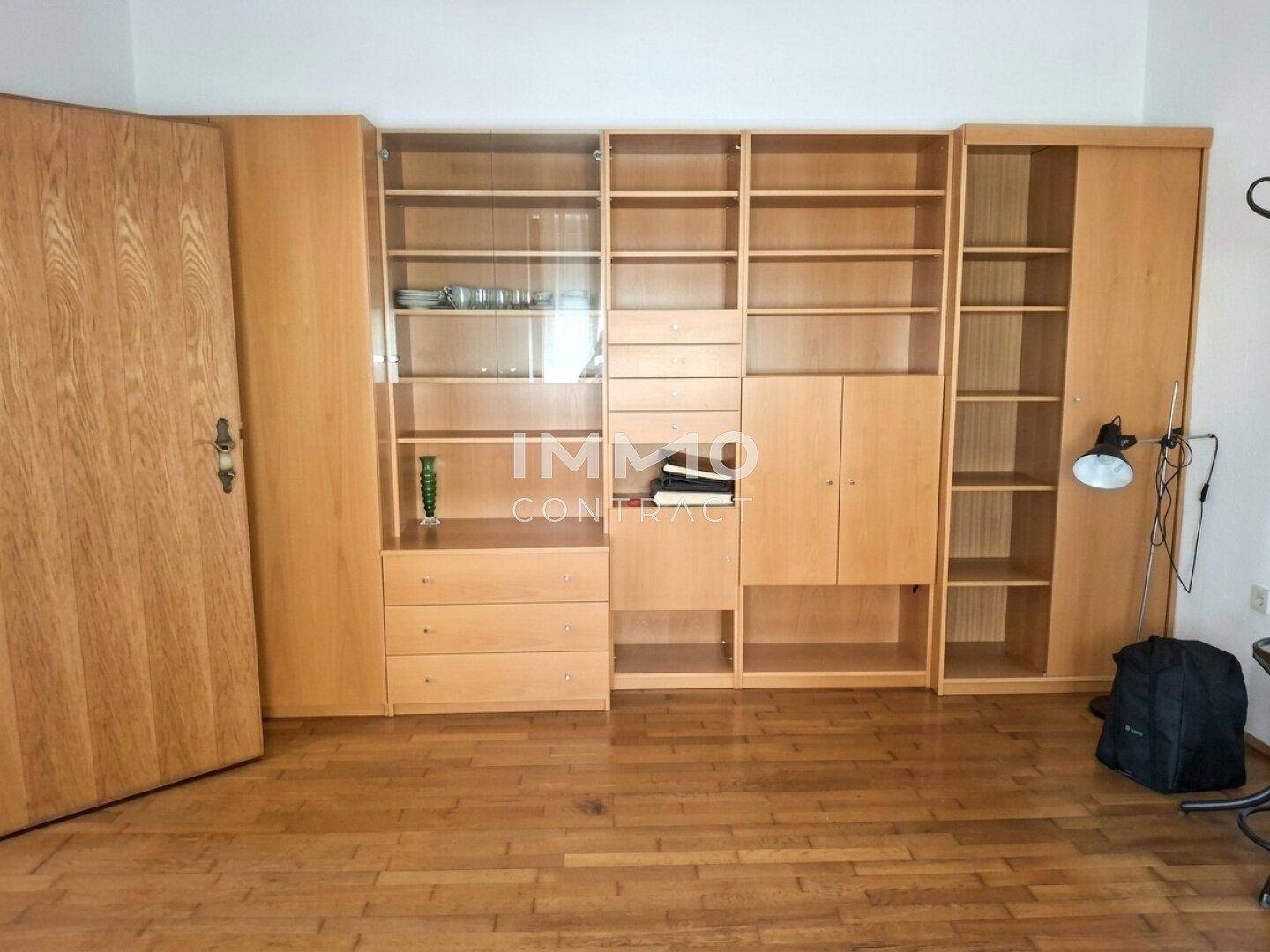 Wohnzimmer mit großen Holzregalen, Parkettboden und viel Stauraum.