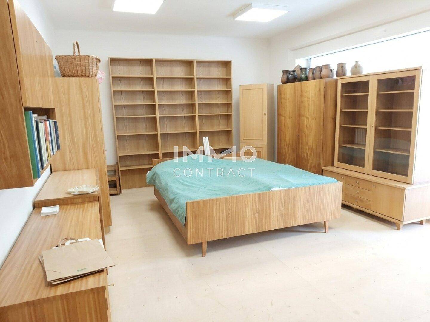 Geräumiges Schlafzimmer mit Holzbett, Regalen und Schränken.
