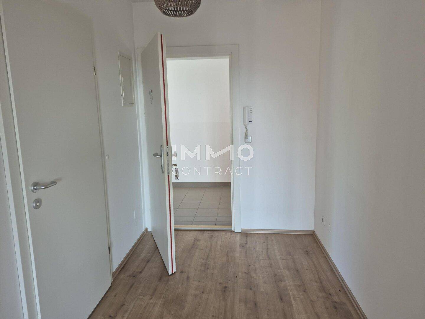 Heller Flur mit Laminatboden und weißen Wänden, der zu weiteren Räumen führt.