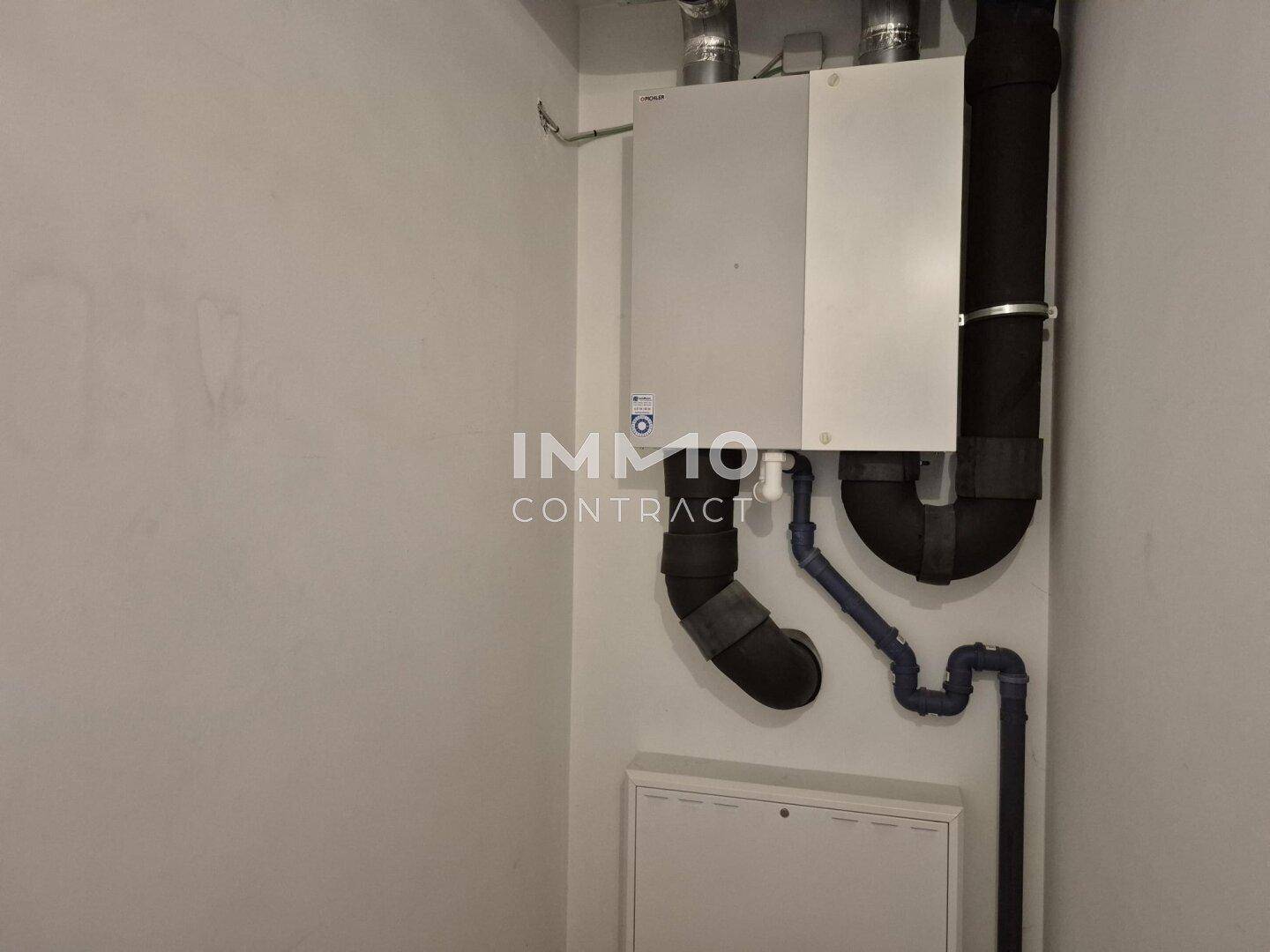 Technikraum mit Heizungsanlage und sichtbaren Rohren an der Wand.
