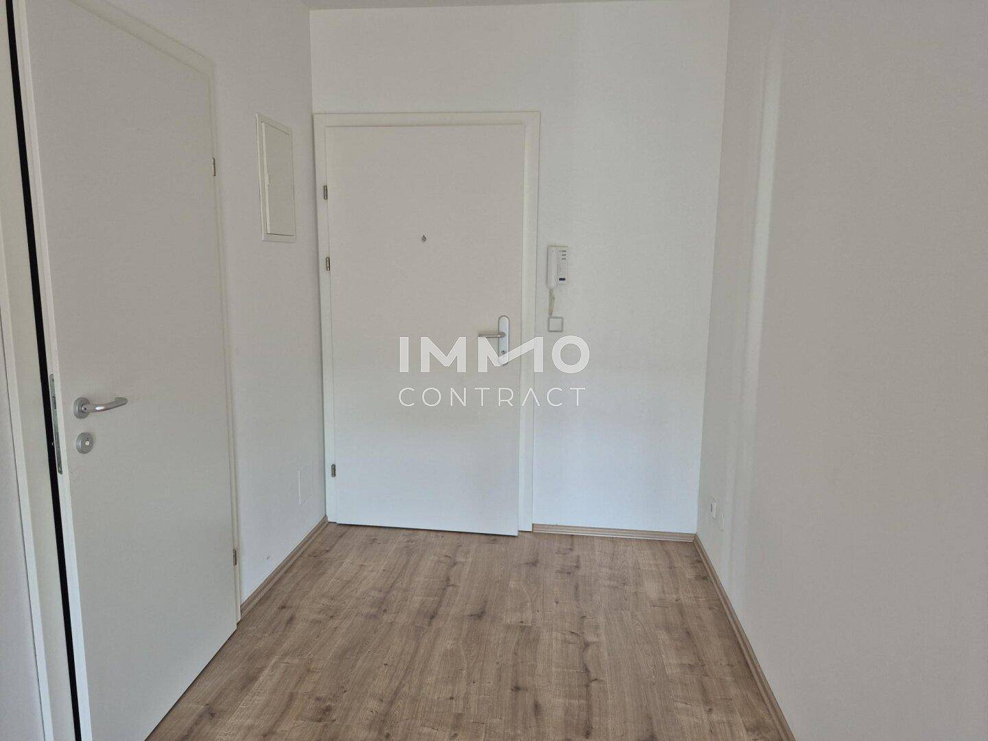 Geräumiger Flur mit Laminatboden und weißer Eingangstür, bereit zur individuellen Gestaltung.
