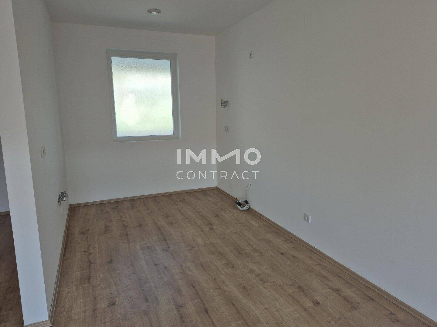 Helles, leeres Zimmer mit Laminatboden und einem Fenster, ideal als Schlaf- oder Arbeitszimmer.