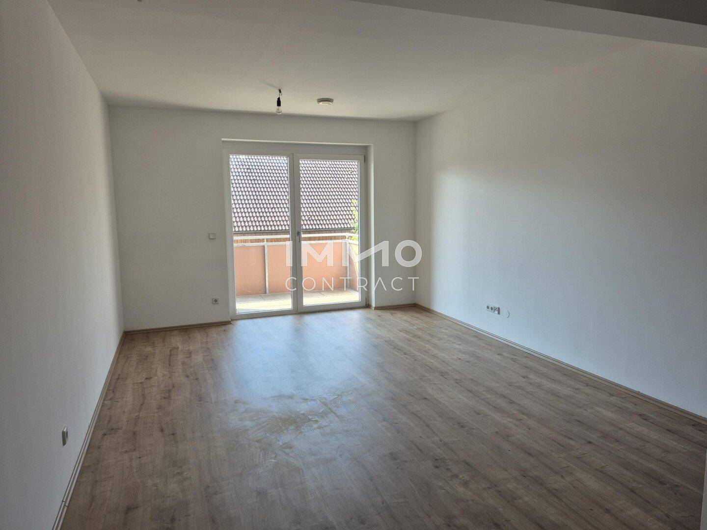 Großes, helles Wohnzimmer mit Laminatboden und direktem Zugang zu einem Balkon.