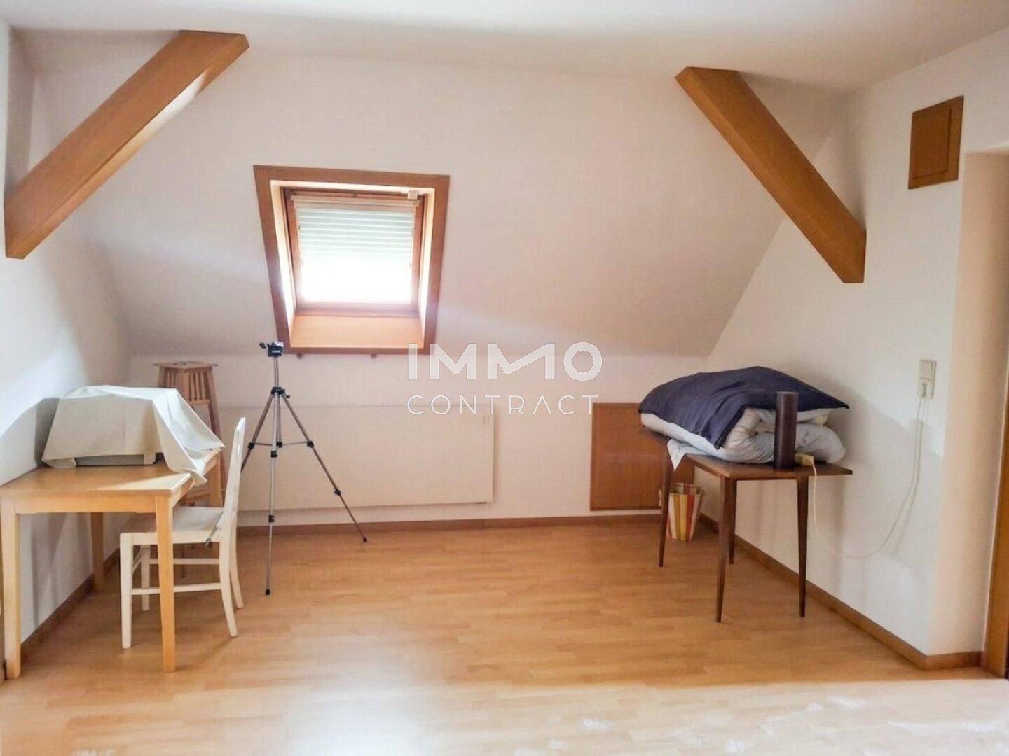 Dachzimmer mit Schreibtisch, Dachfenster und Laminatboden.