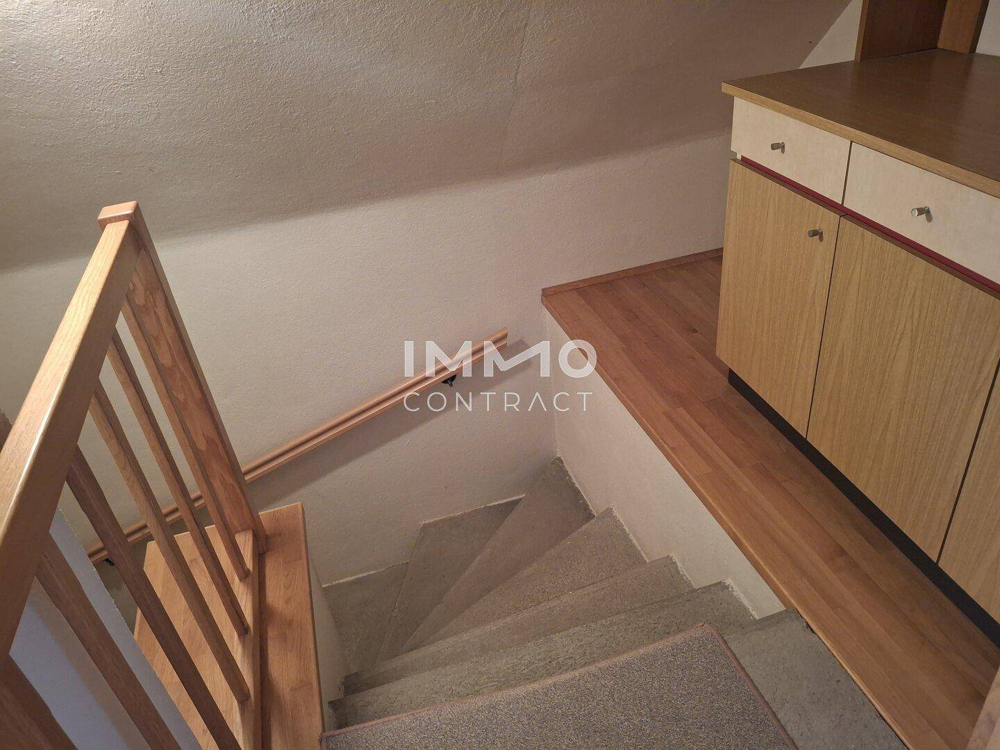 Treppenhaus mit Holzgeländer und Teppichstufen, führt in die obere Etage.