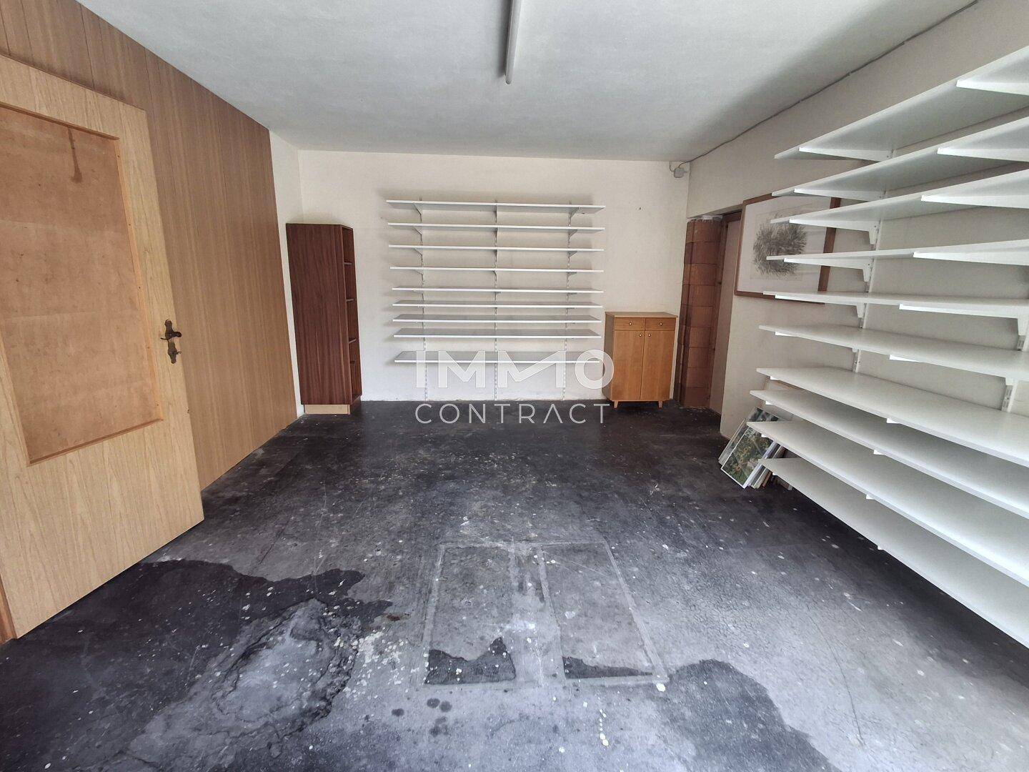 Großer Abstellraum mit Regalen und dunklem Boden.