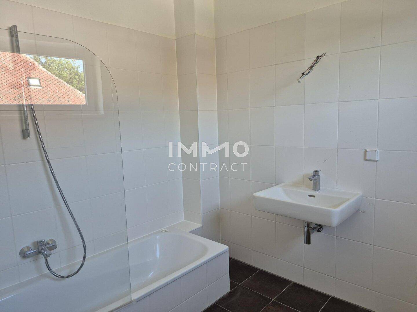 Badezimmer mit Badewanne, Waschbecken und weißen Fliesen, inklusive Fenster.