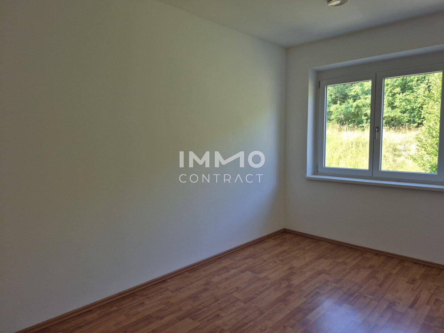 Ruhiges Zimmer mit Fenster und Blick auf grüne Bäume und Wiesen.