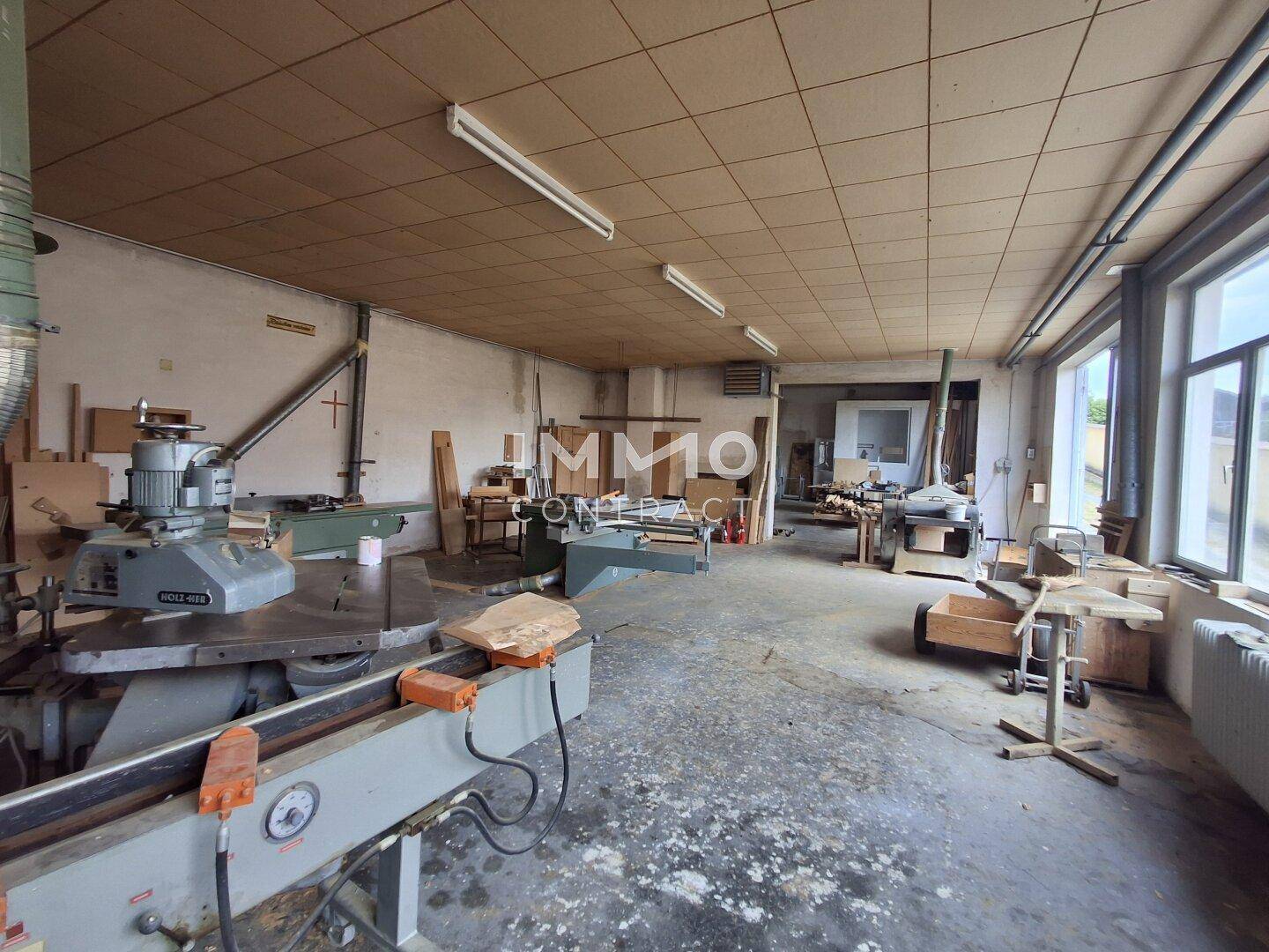 Große Werkstatt mit verschiedenen Maschinen und großen Fenstern.