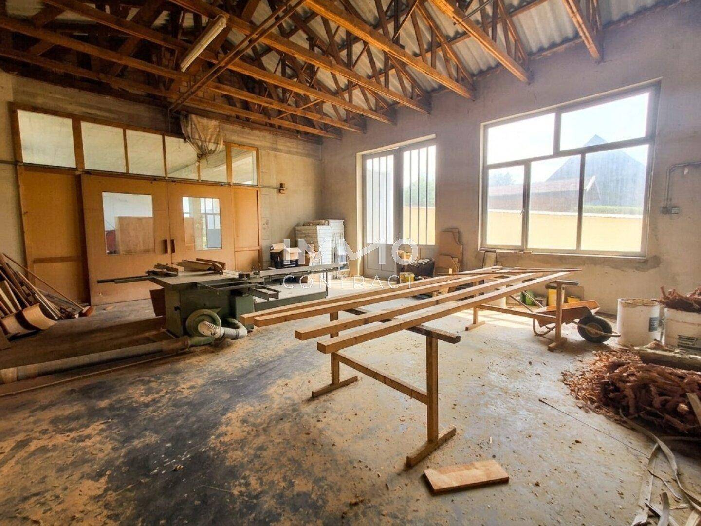Geräumiger Werkstattbereich mit Holzbalken, großen Fenstern und Arbeitsflächen.