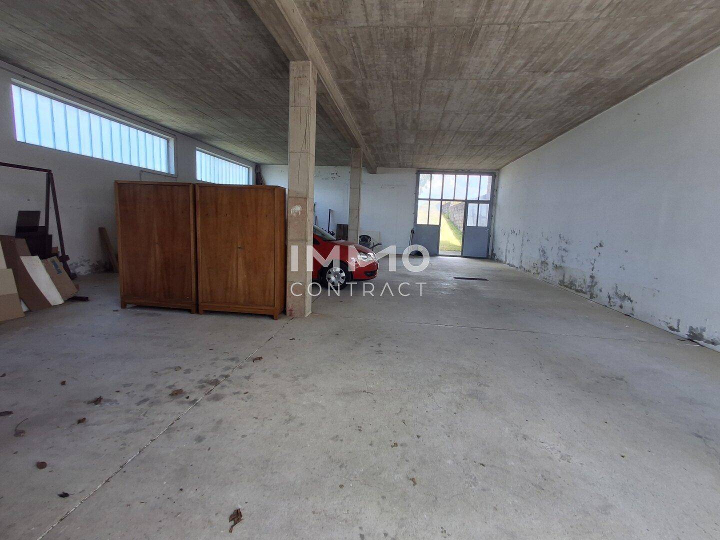 Großer, leerer Raum mit Betonboden, hohen Decken und Tageslichtfenstern.