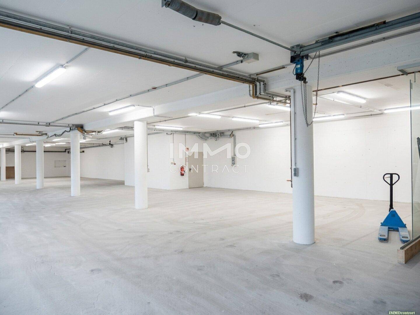 Helle und geräumige Lagerfläche mit Betonboden, Säulen und sichtbaren Installationen.