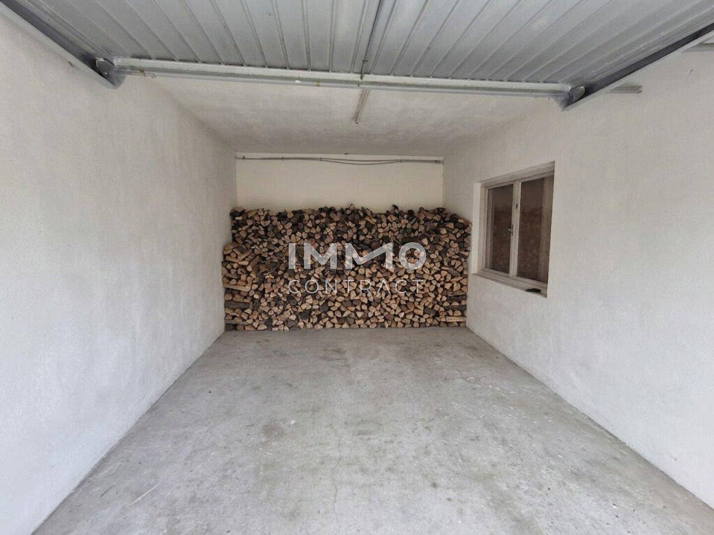 Lagerraum mit gestapeltem Brennholz und einem kleinen Fenster.
