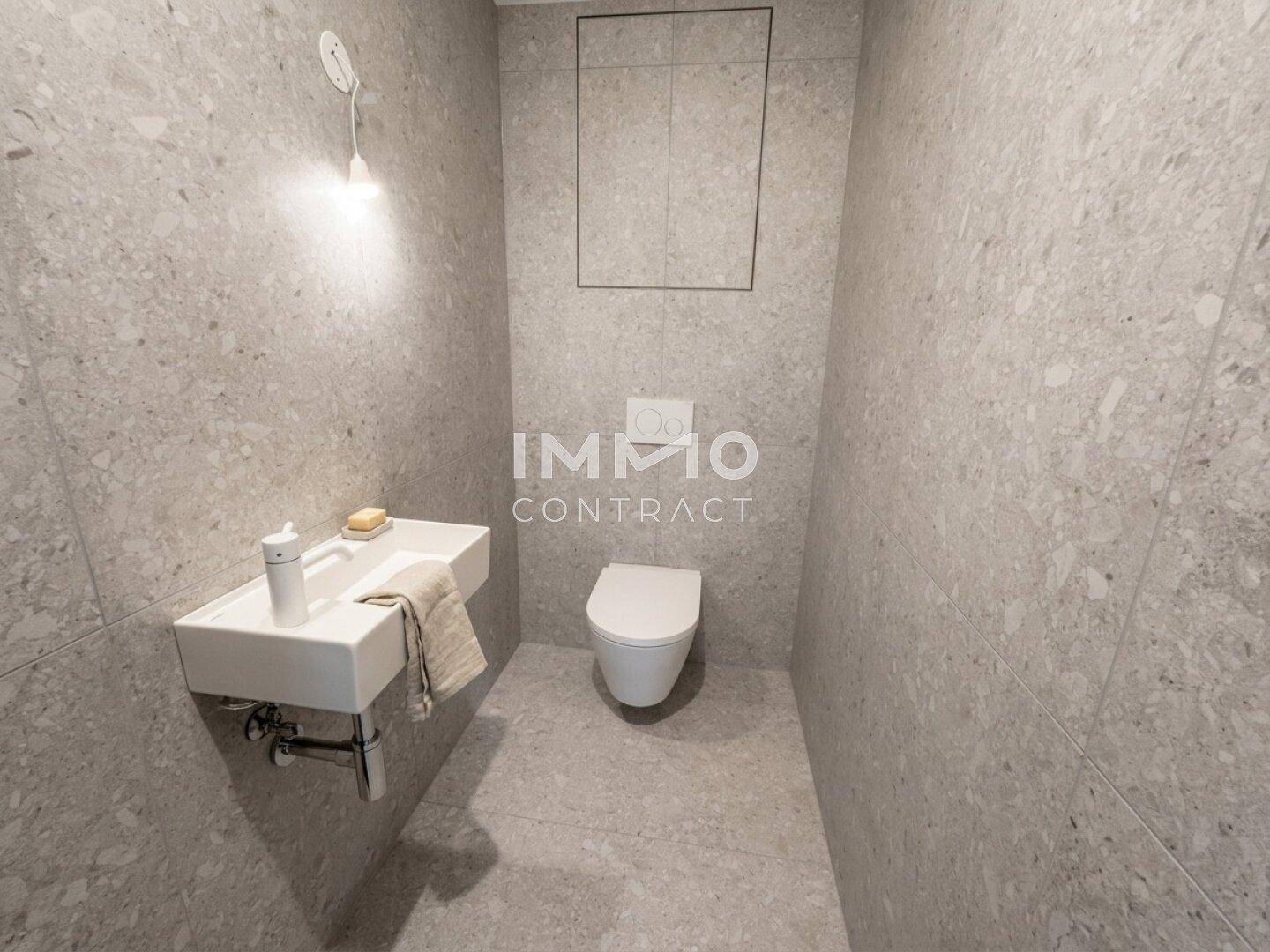 Modernes Gäste-WC mit schwebendem Waschbecken und Wand-WC in grauen Fliesen.